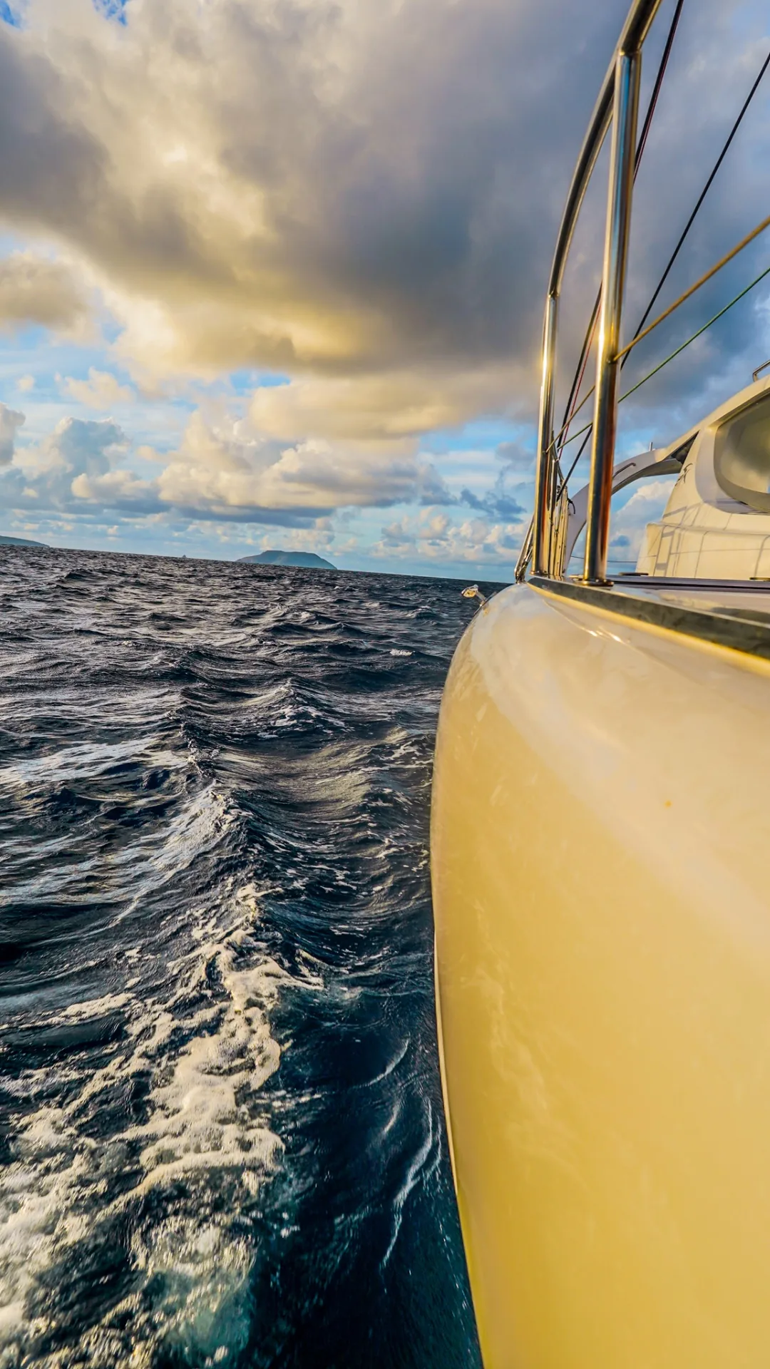 View along the hull of Stella Blue catamaran underway with whitecaps and a distant Virgin Islands peak